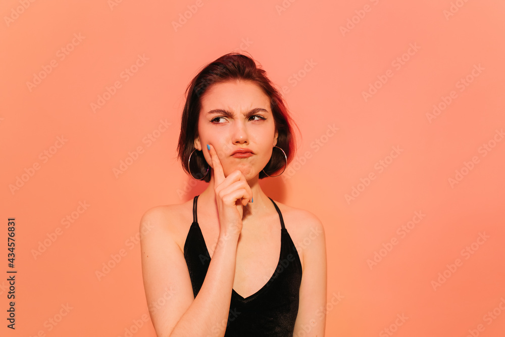 thoughtful young woman looking away holding hand near face on orange background thoughtful young woman looking away holding hand near face on orange background