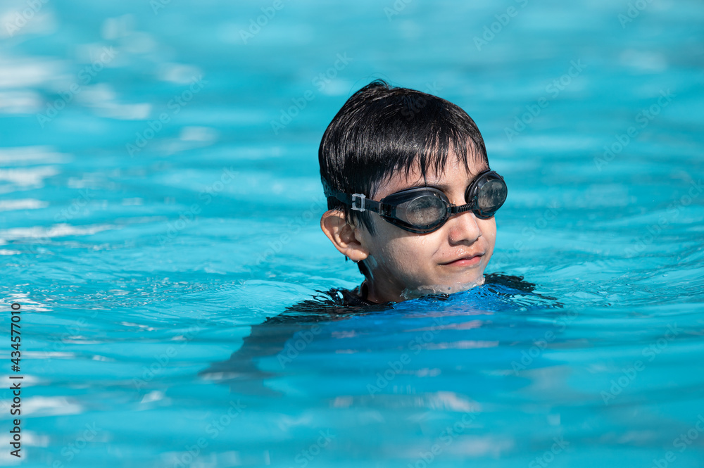 A 7-year-old boy swims in the sea at dawn with glasses for swimming