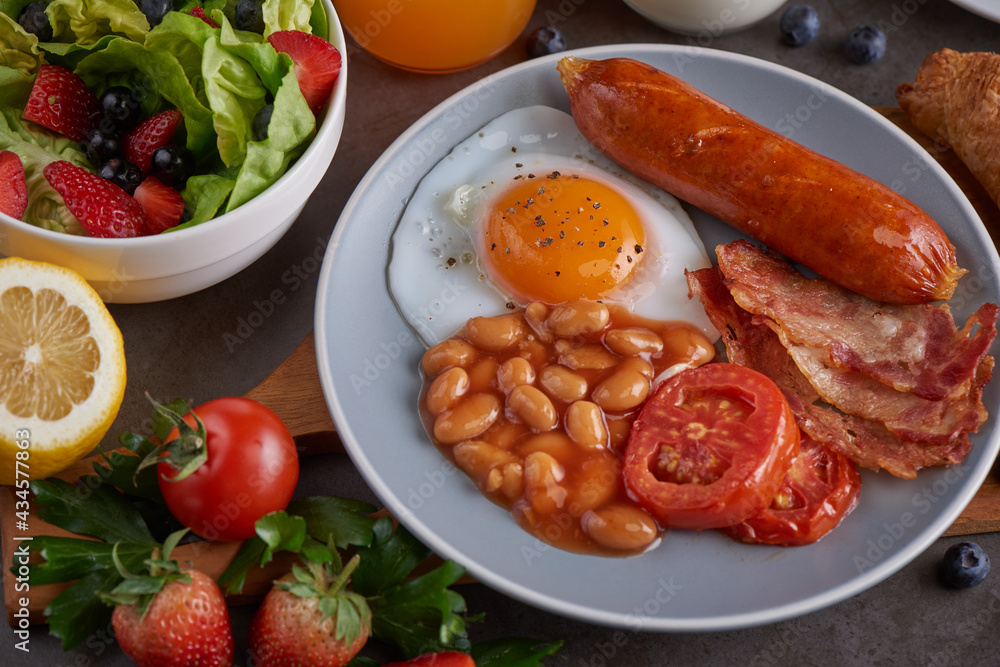 Delicious breakfast with fresh croissants, bacon, beans, sausage with fried egg, tomato and coffee served, milk, orange juice. strawberry, butterhead, blackberry salad. full american healthy breakfast Delicious breakfast with fresh croissants, bacon, beans, sausage with fried egg, tomato and coffee served, milk, orange juice. strawberry, butterhead, blackberry salad. full american healthy breakfast