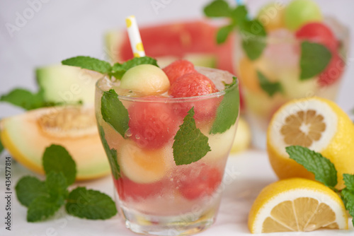Refreshing summer citrus cocktail with lemon, watermelon and melon with mint and ice cubes in glass, homemade fresh fruit, fruit drink for healthy concept, selective focus.