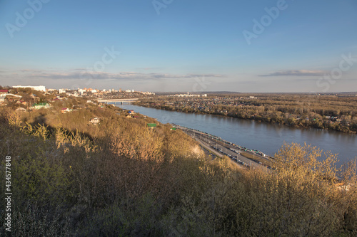 Nice view from the mountain to the river and the city. City on the river bank. Evening warm sunlight. Blue sky.