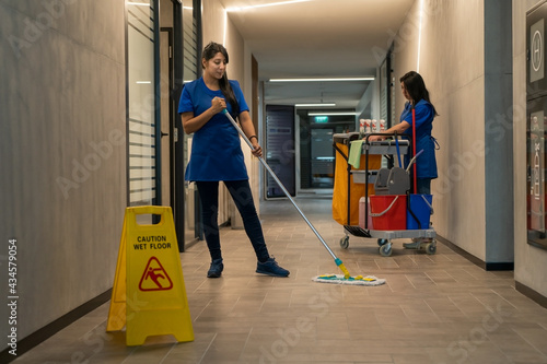 Cleaner mops the floor while the other prepares the detergents