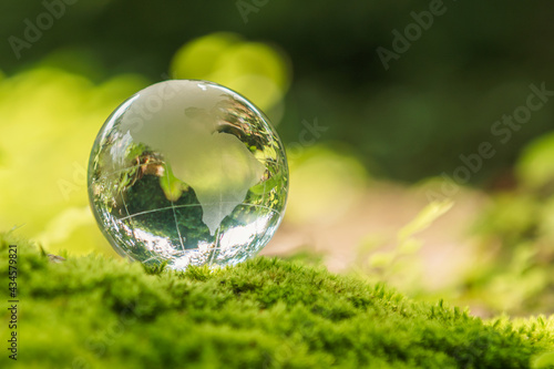 crystal globe glass resting on moss stone with sunshine in nature forset. eco  environment concept © lovelyday12