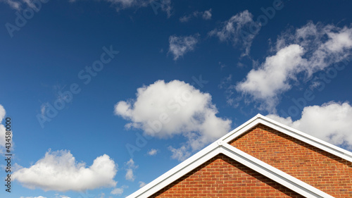 House roof against blue sky with white clouds