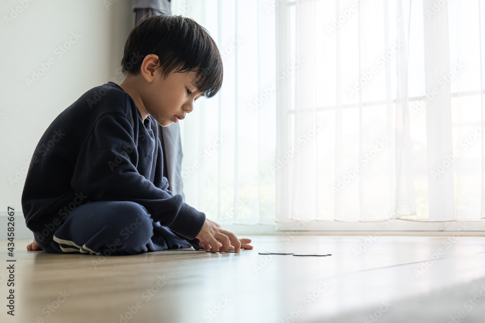 Asian boy building paper jigsaws on the house floor. Asian boy building paper jigsaws on the house floor.