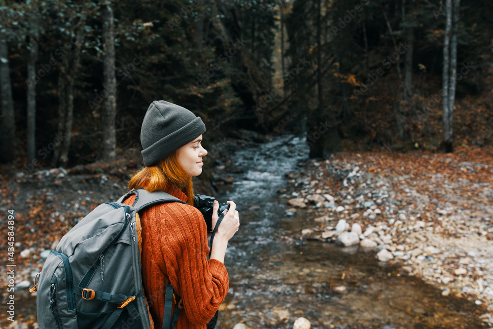 woman with a camera near a pond in the mountains on nature and trees