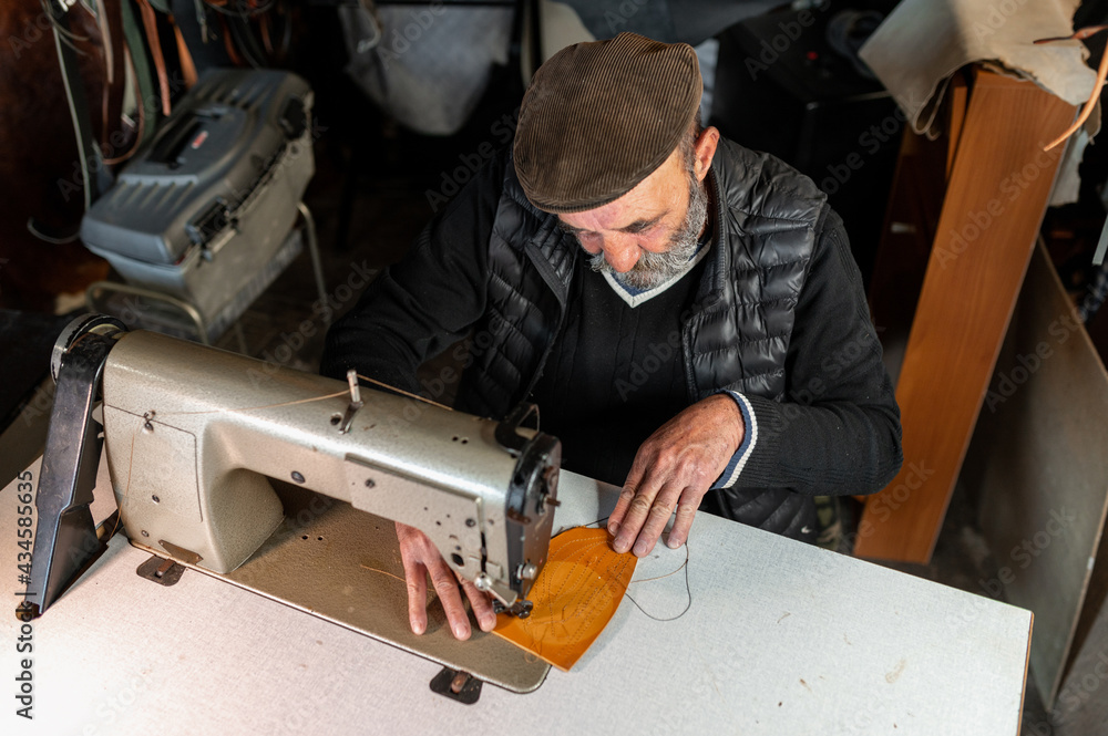 Top view old man in workshop making leather goods working with sewing machine Top view old man in workshop making leather goods working with sewing machine
