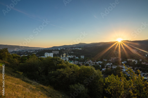 Sunrise over mountains and town Kislovodsk in bright sunlight.