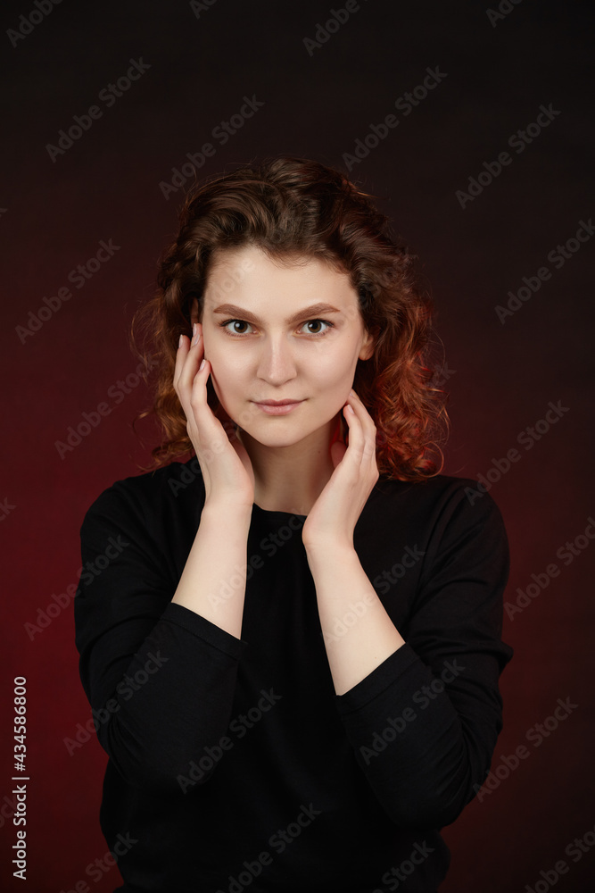 Portrait of a young attractive girl in black clothes on a dark background. Close-up with hands in the frame. Portrait of a young attractive girl in black clothes on a dark background. Close-up with hands in the frame.