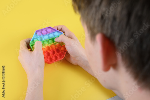 Teenger playing with popular silicone colorful antistress pop it hexagon toy. Close up. photo