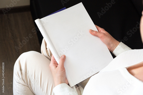 Hand holds white magazine with blank cover mock up. Hand in shirt hold clear magazine mockup template. A4 book softcover surface design.