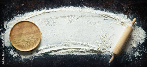 Abstract baking background with the rolling pin and flour on dark table photo