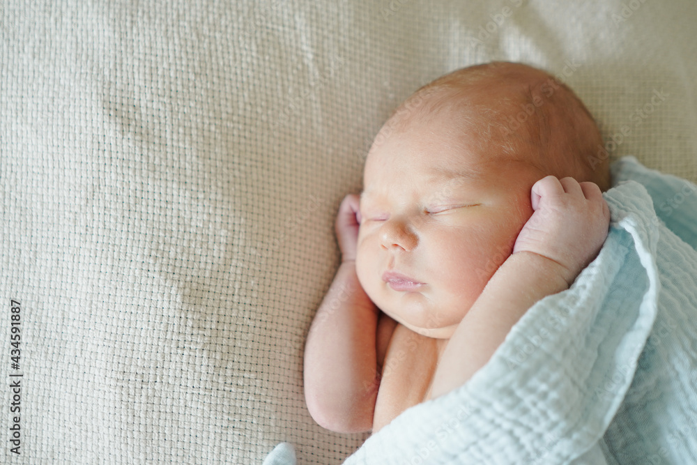 Cute infant lying on soft bed under blanket and sweetly sleeping at daytime