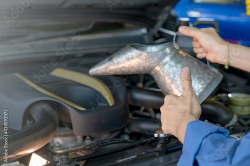 Close up thumbs up hand of garage worker or technician man hold bucket of engine oil or lubricant in front of car during maintenance or fix the problem in workplace.