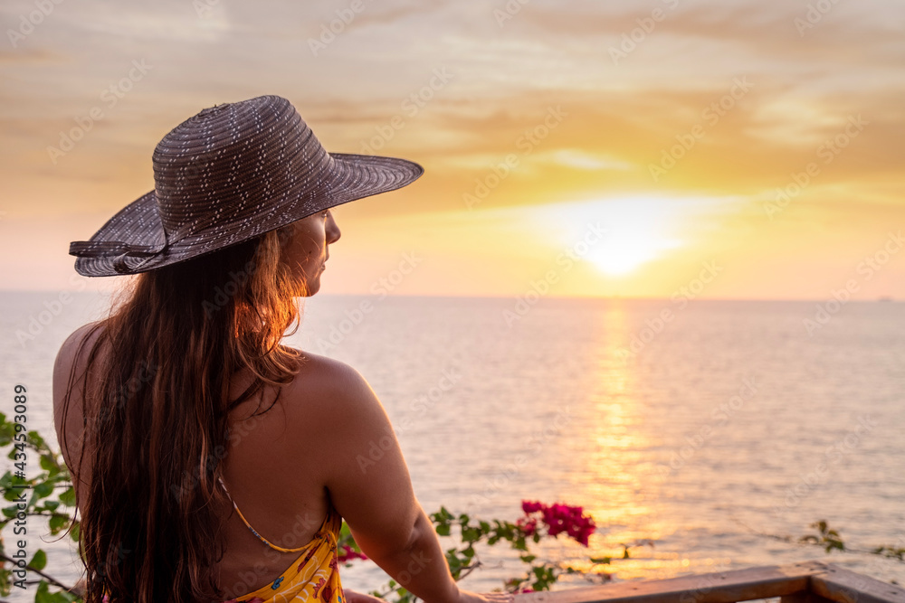 woman with hat watching the sunset