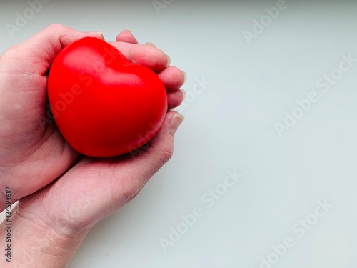 Fototapeta Naklejka Na Ścianę i Meble -  A red heart in the hands of a person. Copy space. Isolated on white background.