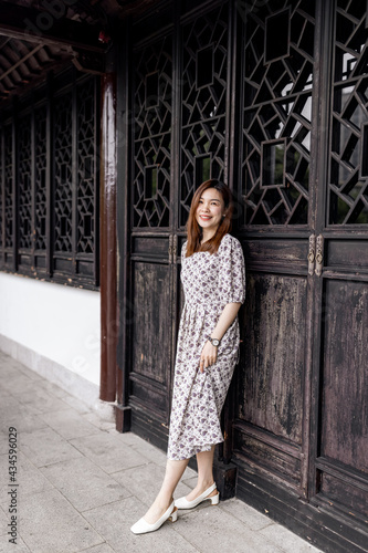 Portrait of young asian woman wearing stylish summer dress and walking outdoor in old city. Happy stylish woman with smiley face enjoys life © Алина Бузунова