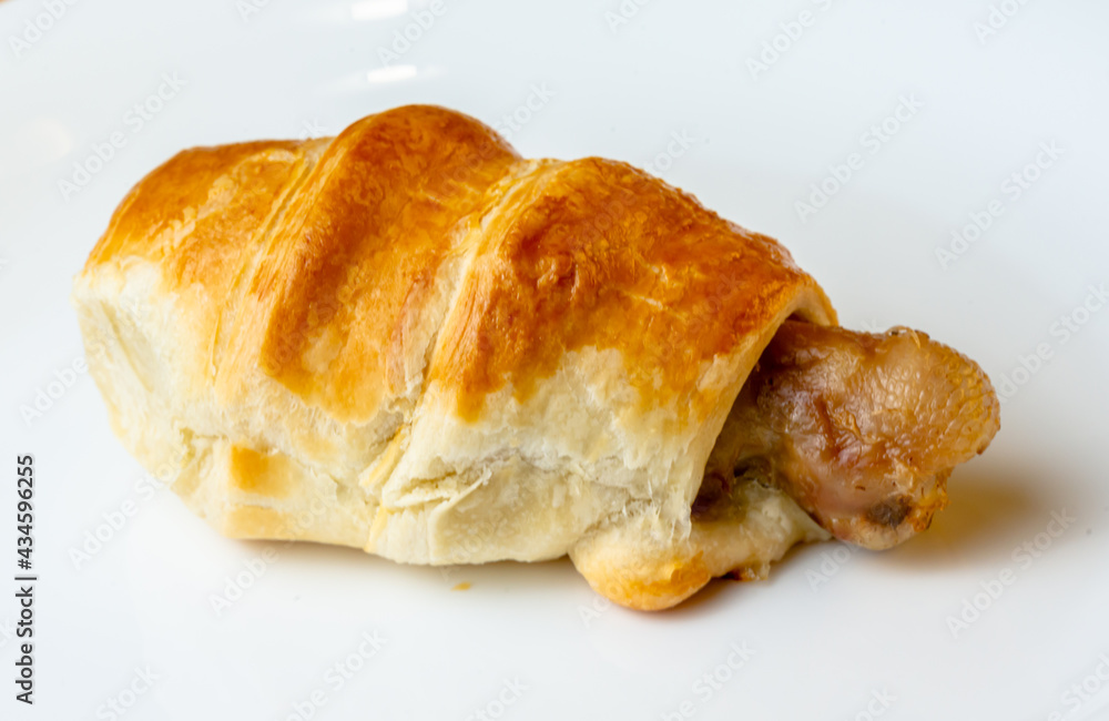 Appetizing chicken leg in puff pastry on a white plate Appetizing chicken leg in puff pastry on a white plate
