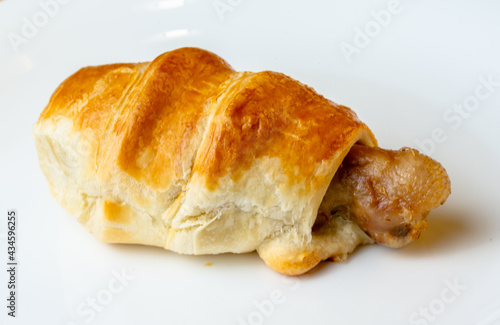 Appetizing chicken leg in puff pastry on a white plate