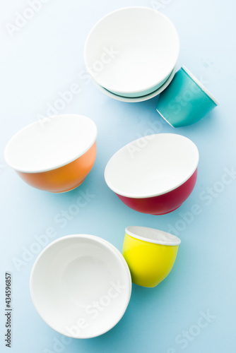 Colored bowl orange ,yellow pink ,blue and green color flatlay, over a blue wallpaper type background, top view, flatlay