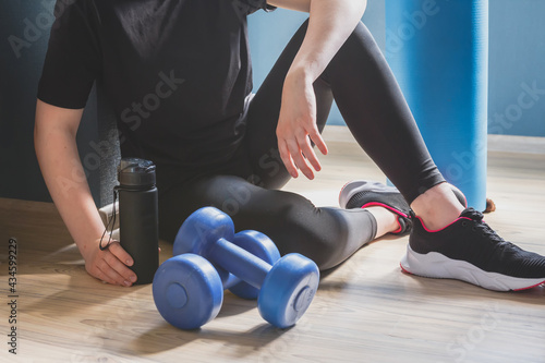 Fit,sport.Home fitness,remote training online with virtual instructor.Woman in sportswear sitting floor with dumbbells home. Sports and recreation concept lockdown with fitness apps online.Home fit