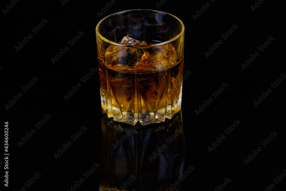 Glass of whiskey with ice on a black background