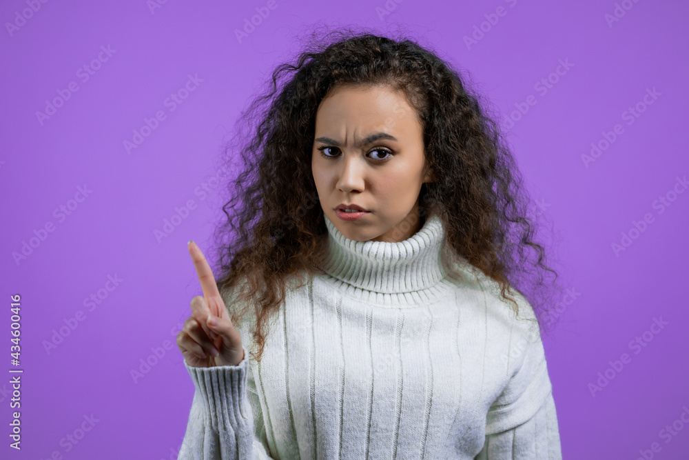 Portrait of serious woman showing rejecting gesture by stop finger sign. Girl in sweater isolated on violet background. Portrait of serious woman showing rejecting gesture by stop finger sign. Girl in sweater isolated on violet background.