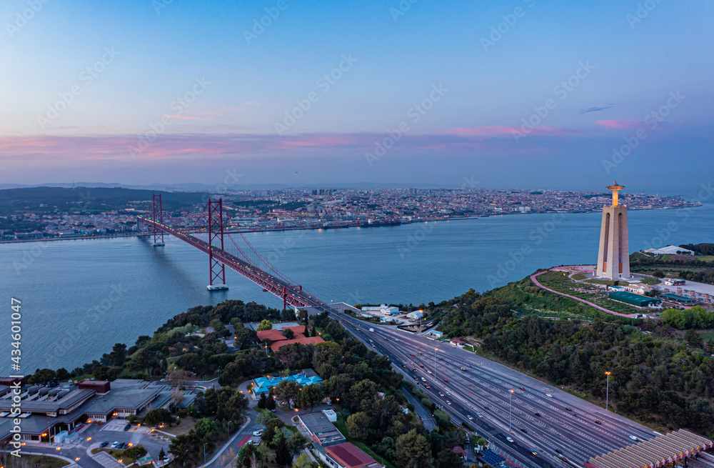 Aerial view of multilane road leading on suspension bridge over Tagus river in twilight time, Lisbon, Portugal.