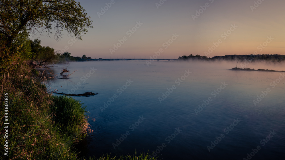 Mglisty wschód słońca nad rzeką Wisłą z mostem w tle i parującą wodą w Annopolu w województwie Lubelskim