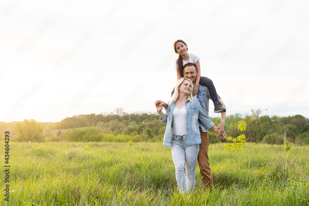 Happy family in the park evening light. The lights of a sun. Mom, dad and baby happy walk at sunset. The concept of a happy family Happy family in the park evening light. The lights of a sun. Mom, dad and baby happy walk at sunset. The concept of a happy family