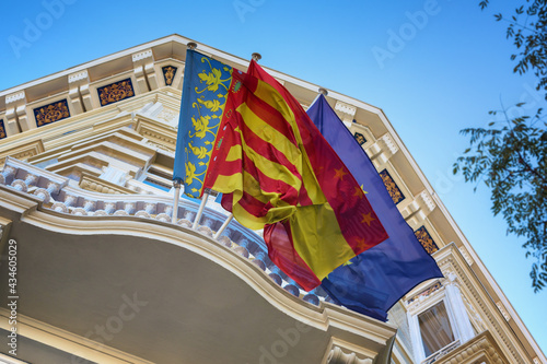 Waving flags of Valencia, Spain and European Union (EU) at the balcony of decorated administrative building, perspective view