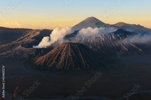 Clouds of smoke on Mount Bromo volcano, Indonesia. Aerial view of Mount as active volcano with crater in depth. Sunrise behind mountains.