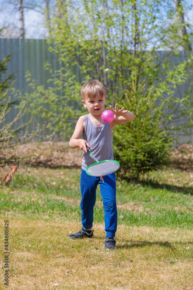A fair-haired child plays badbinton on the lawn. A fair-haired child plays badbinton on the lawn.