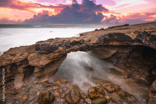 Arch shaped rock formation in the coastline at the sunset. Long exposure