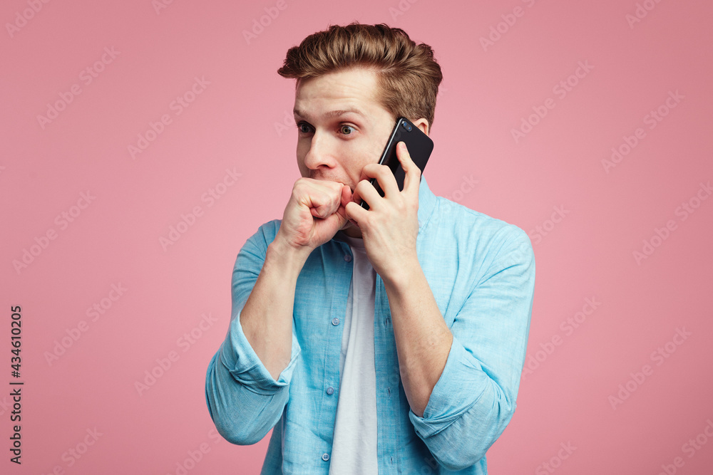 Nervous male keeps fists in mouth during conversation via smartphone Nervous male keeps fists in mouth during conversation via smartphone