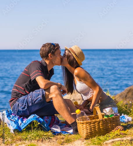 Romantic scene of a Caucasian couple kissing at the picnic in the mountains by the sea enjoying the heat, summer lifestyle
