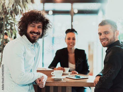 A group of business people on a coffee break use laptops, tablets and smartphones while discussing new business projects.  photo