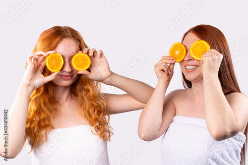Pretty adorable joyful attractive hilarious funny comic positive nude natural pure red-haired girls having two pieces of orange closing both eyes isolated on gray background with copy space for ad