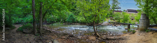  a stunning panoramic shot of the rushing river water of Big Creek river with lush green trees and large rocks on the banks and in the middle of the river at Vickery Creek in Roswell Georgia photo