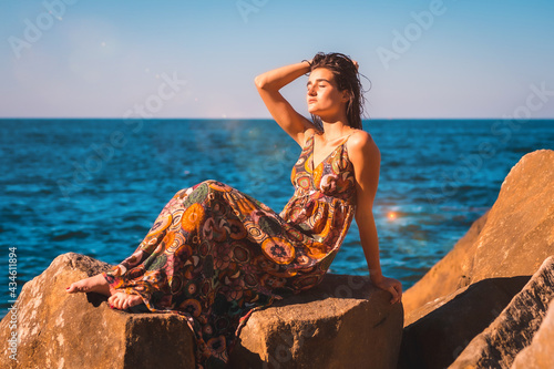 A young brunette with wet hair and a floral dress by the sea, summer llifestyle photo