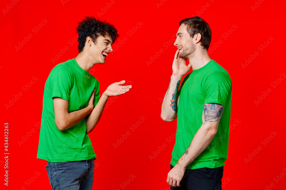 two men in green t-shirts stand next to communication Friendship red background two men in green t-shirts stand next to communication Friendship red background