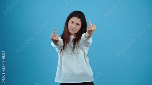 The energetic, annoyed girl looks fuck you with both hands. Asian with dark hair, dressed in a blue blouse, isolated on a dark blue background in the studio. The lifestyle concept of sincere emotions