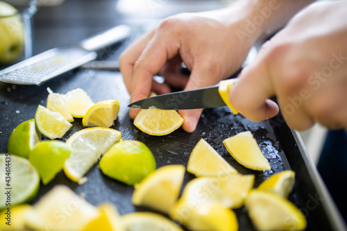 Male hands slicing lemons and limes on a black tray