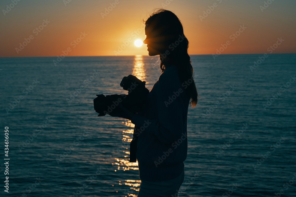 woman photographer with camera at sunset and sea in the background