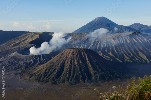 Active volcano with crater in depth, surrounded with lake and covered in clouds of smoke. Mount volcano Gunung Bromo in East Java, Indonesia.