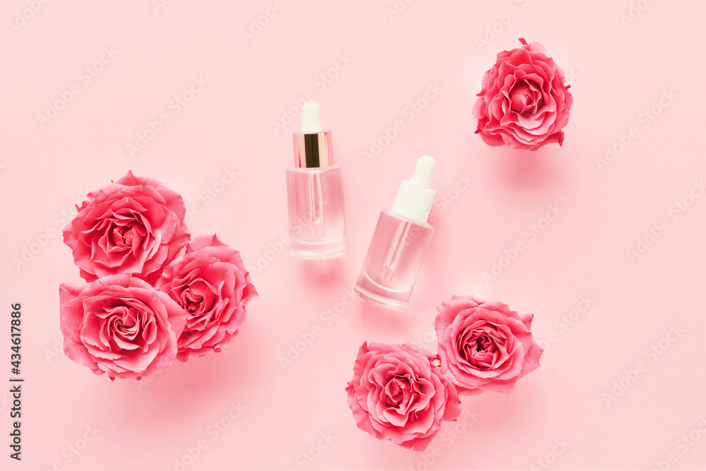 SPA concept. Transparent glass dropper bottles for medical and cosmetic use and pink roses on a pink background. SPA concept. Transparent glass dropper bottles for medical and cosmetic use and pink roses on a pink background.