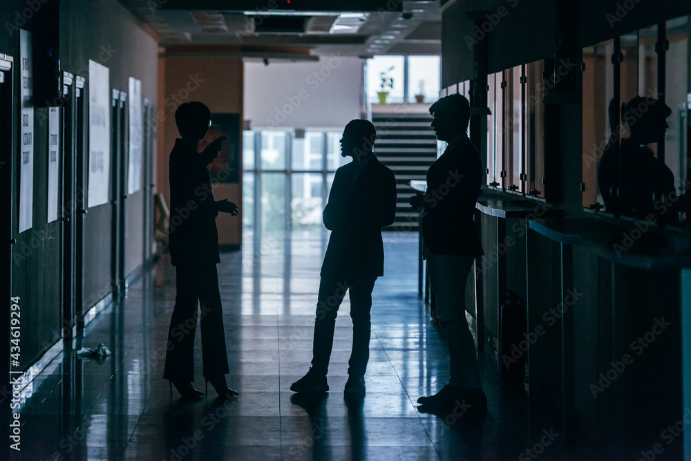 Silhouettes of business people standing in a corporate building.