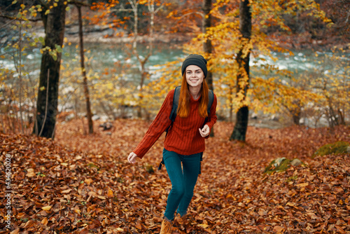 travel tourism woman in sweater and jeans in autumn forest near mountain river