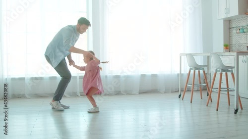 Happy young father and little preschool girl dancing at home.