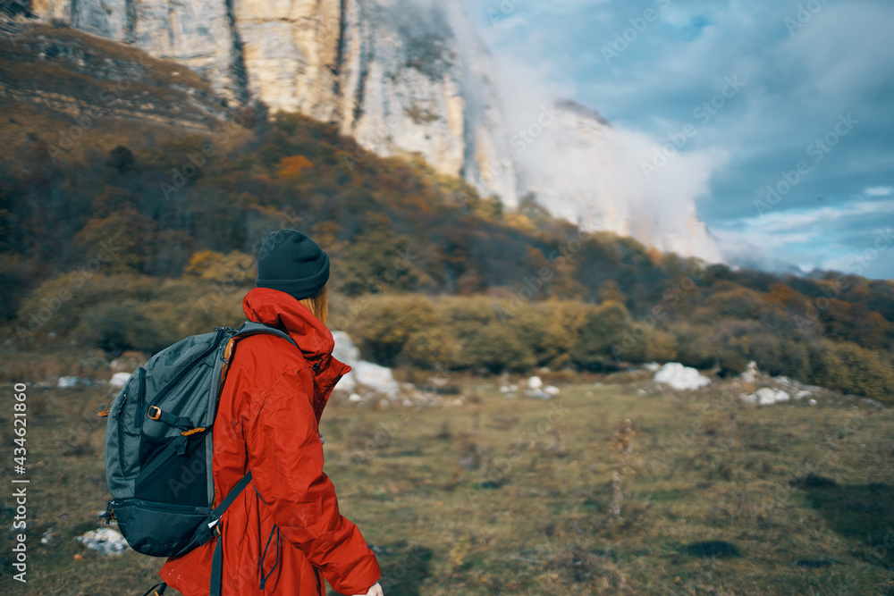 woman in jackets caps with a backpack on her back walks in the fall in the mountains and in nature